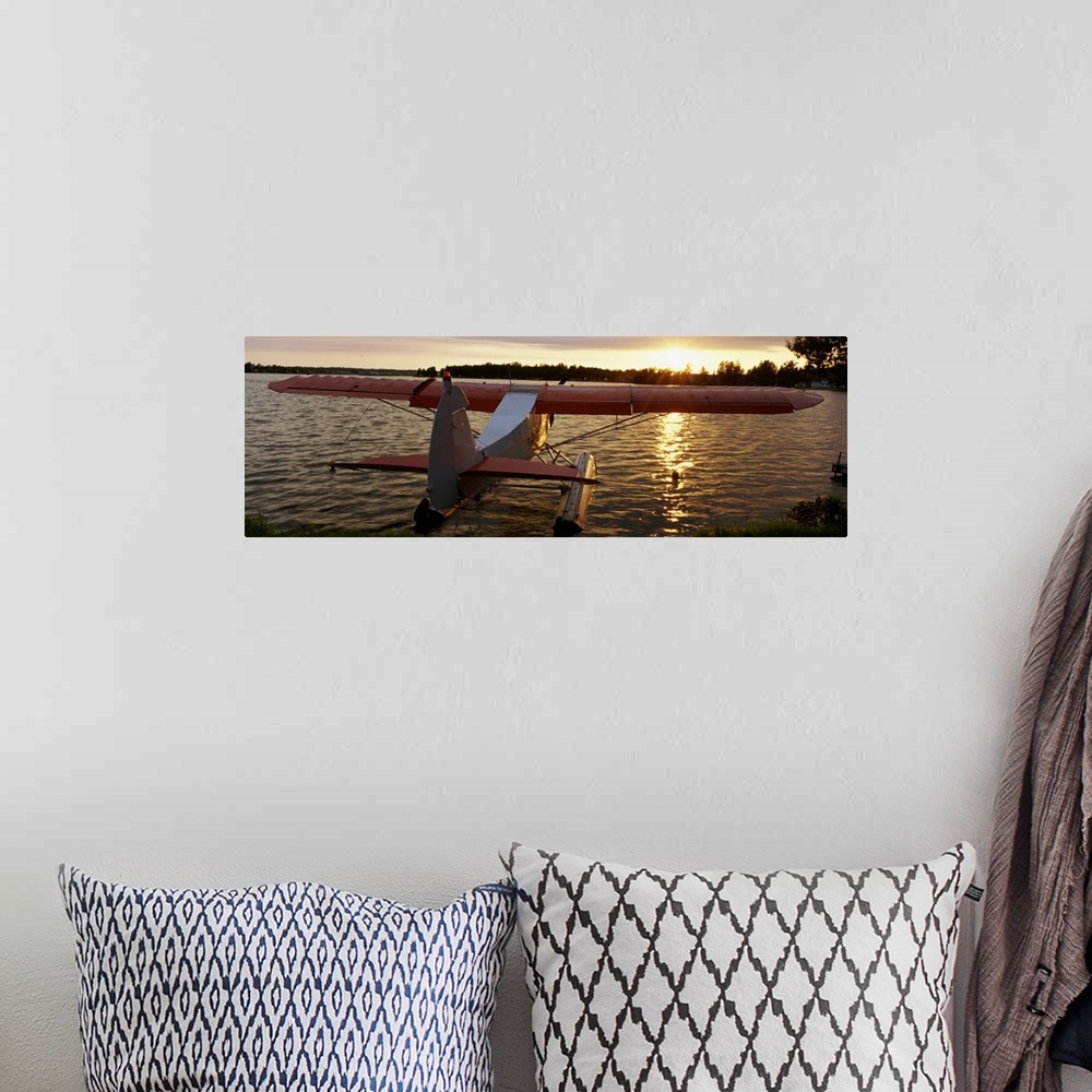 A bohemian room featuring Panoramic photograph of plane sitting in water with forest in the distance at sunset.