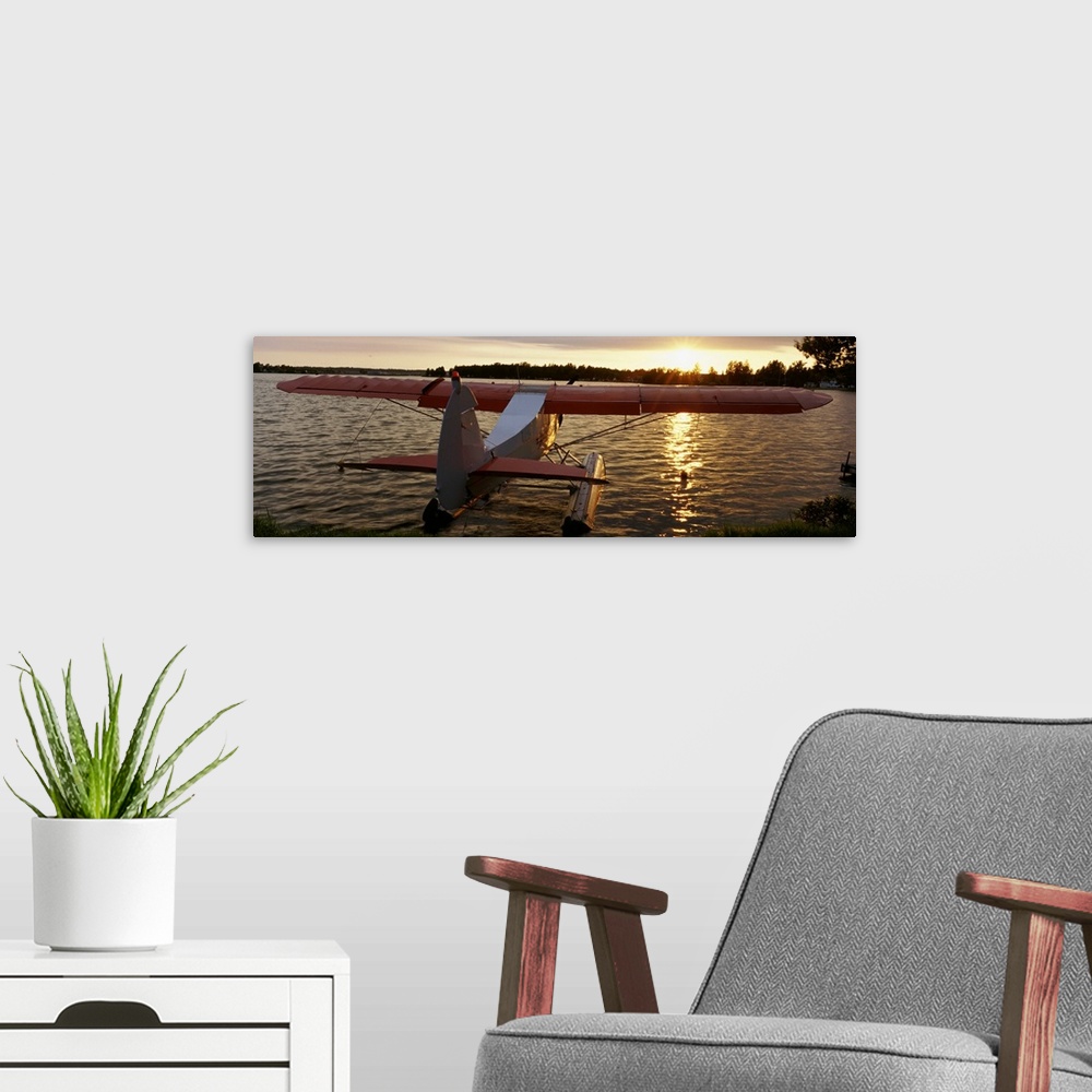 A modern room featuring Panoramic photograph of plane sitting in water with forest in the distance at sunset.