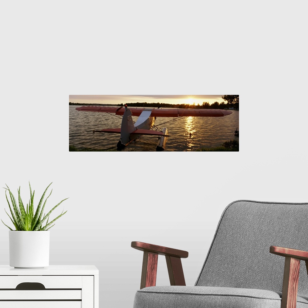 A modern room featuring Panoramic photograph of plane sitting in water with forest in the distance at sunset.
