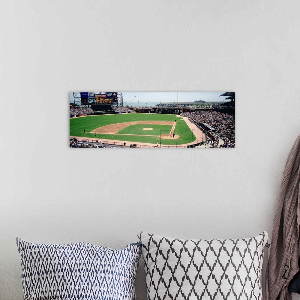 A bohemian room featuring This decorative wall art is a panoramic canvas of a baseball stadium in the middle of a game.