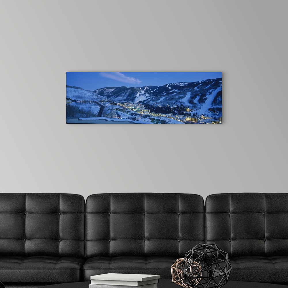 A modern room featuring Panoramic photograph of a  snowy mountain landscape surrounding the brightly lit town of Tellurid...