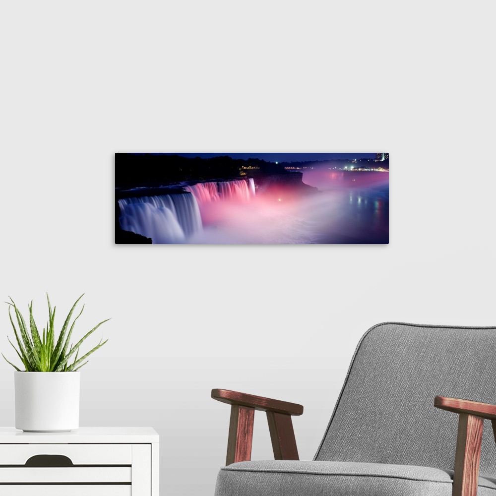A modern room featuring Panoramic photograph of wide stretching waterfall at night with fog rising from the bottom.  Ther...