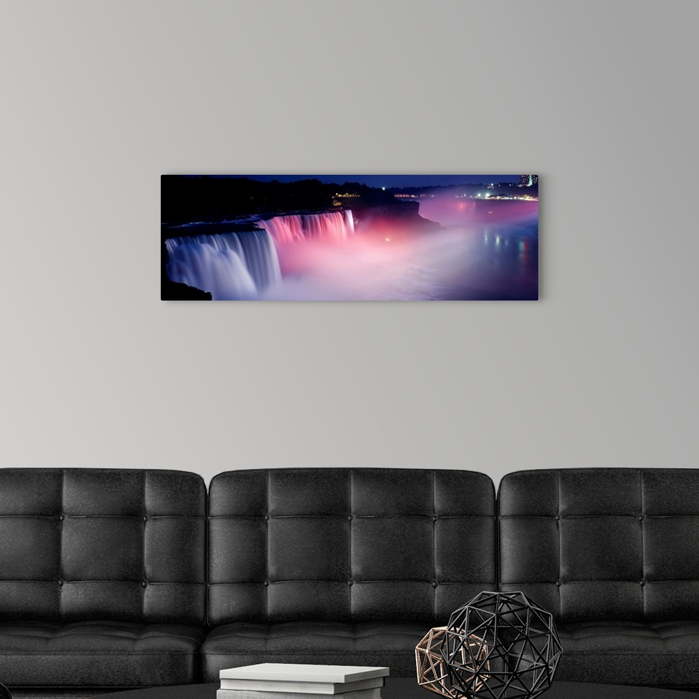 A modern room featuring Panoramic photograph of wide stretching waterfall at night with fog rising from the bottom.  Ther...