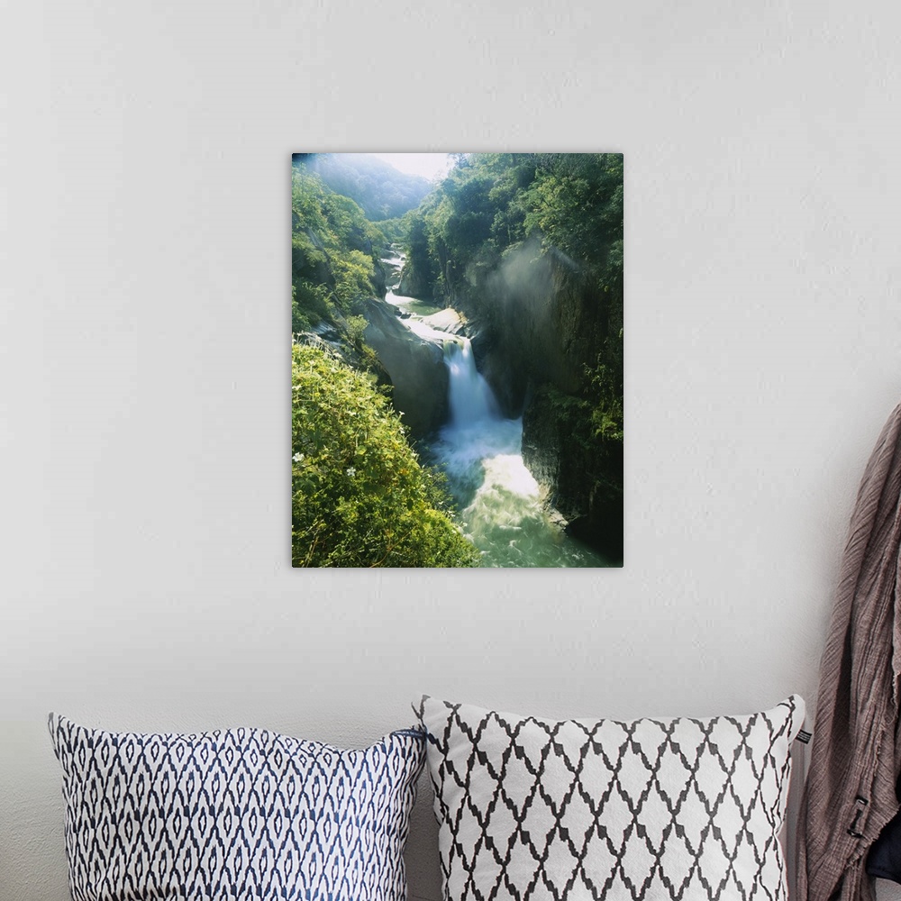 A bohemian room featuring Big aerial photograph of a waterfall surrounded by rocky cliffs and lush, green forest, in Mexico.
