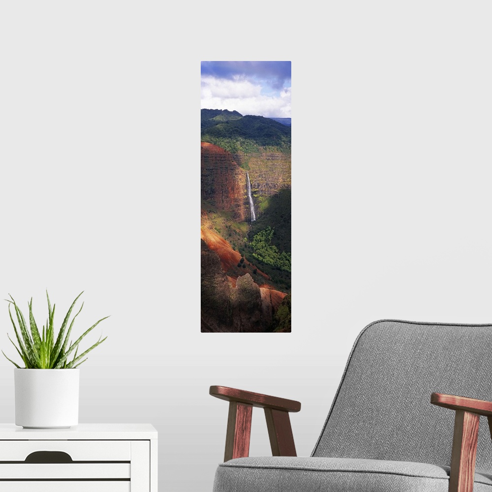 A modern room featuring Tall photo on canvas of a waterfall flowing off of a giant cliff seen from a distance.