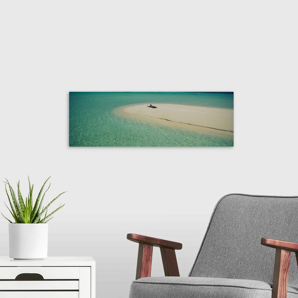 A modern room featuring Panoramic photograph of girl tanning on sand bar surrounded by crystal clear ocean.