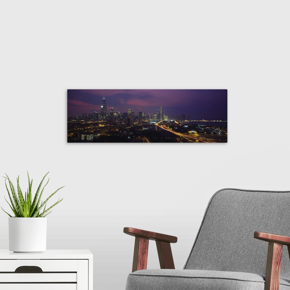 A modern room featuring Panoramic photograph from above of the lights of the Chicago city skyline at night.