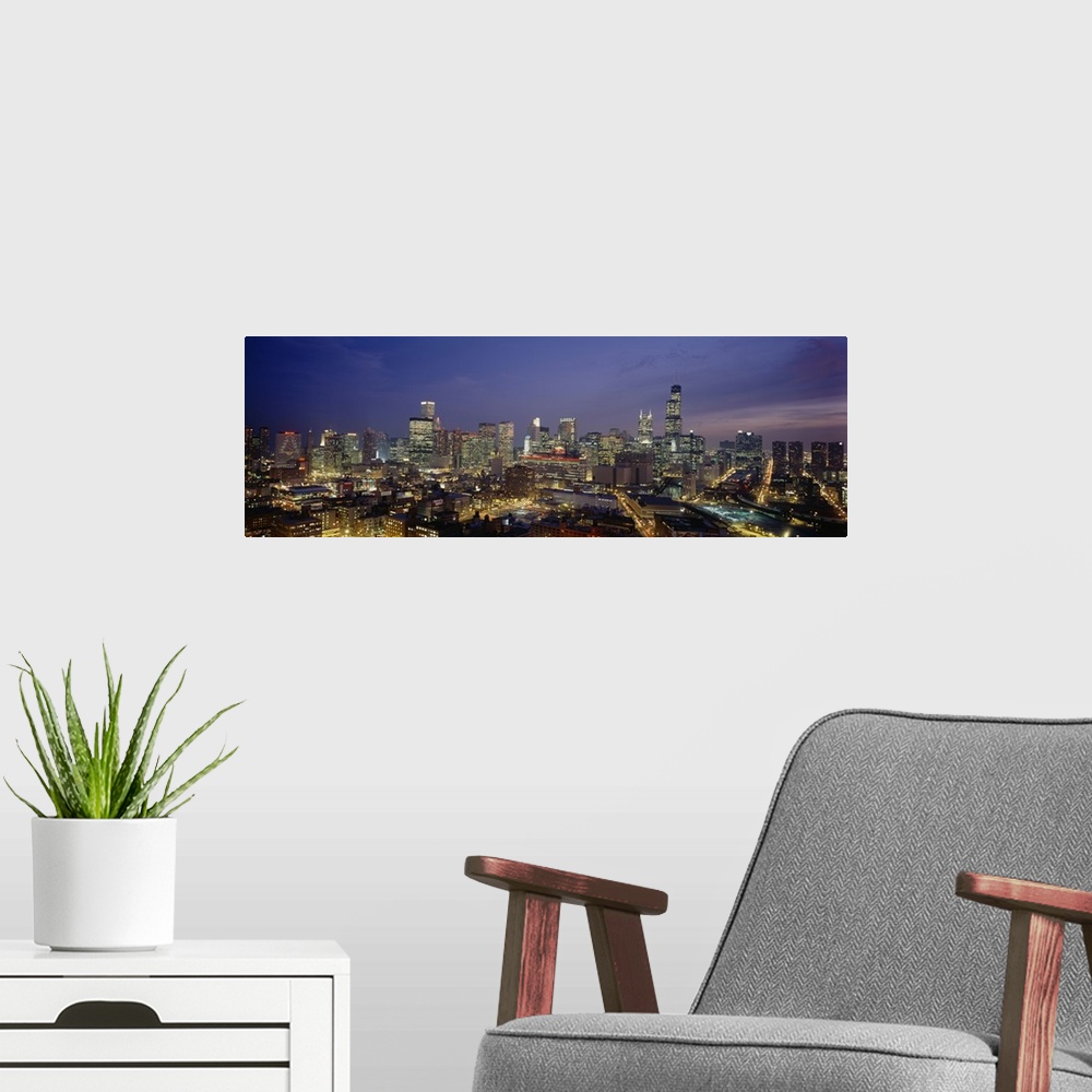 A modern room featuring Panoramic photograph taken of downtown Chicago during the night with all the building windows ill...