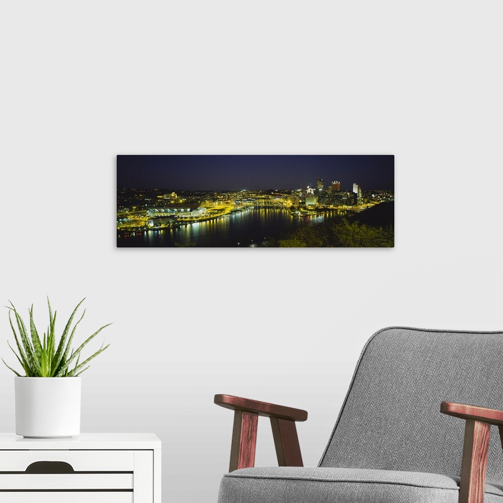 A modern room featuring Panoramic photograph of skyline and waterfront at dusk with tree tops in foreground.