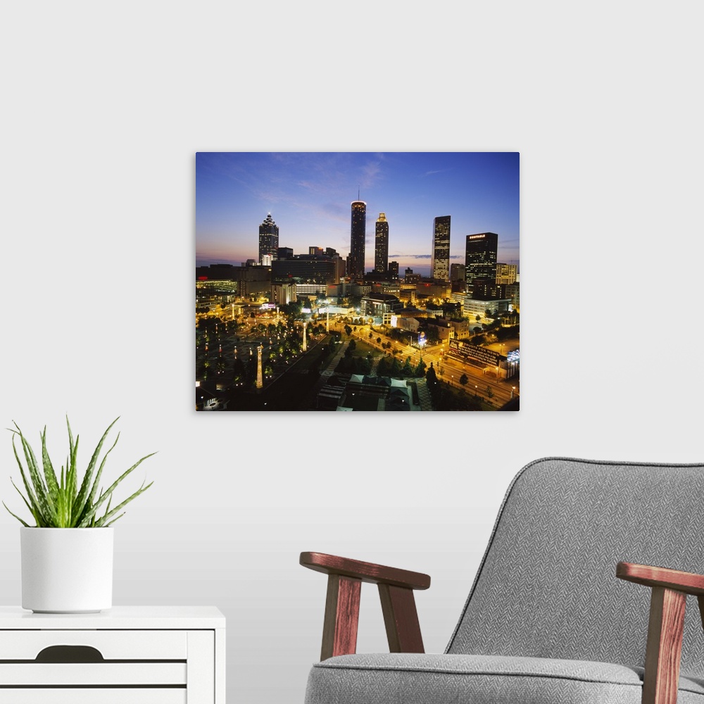 A modern room featuring Big photograph taken as the sun begins to set displays brightly shining skyscrapers and buildings...