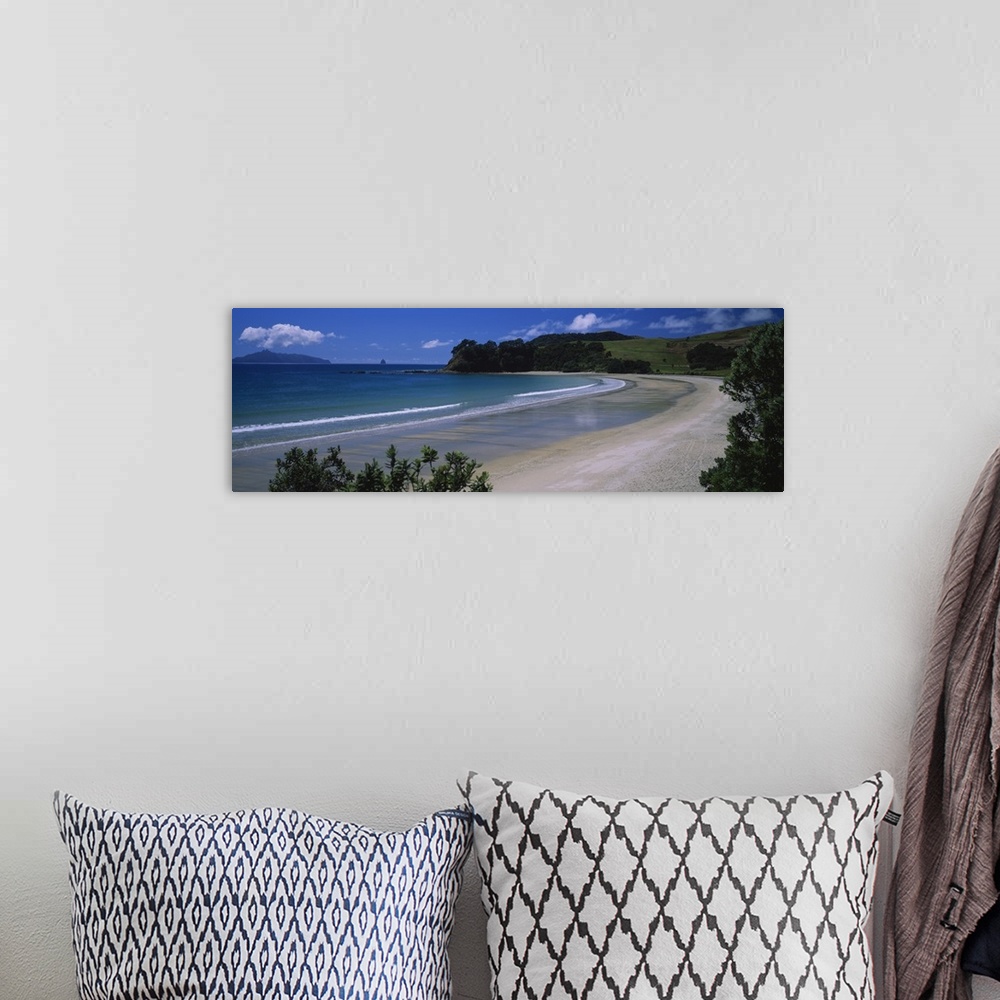 A bohemian room featuring This large panoramic photograph is taken from the New Zealand coast with a large hill in the dist...