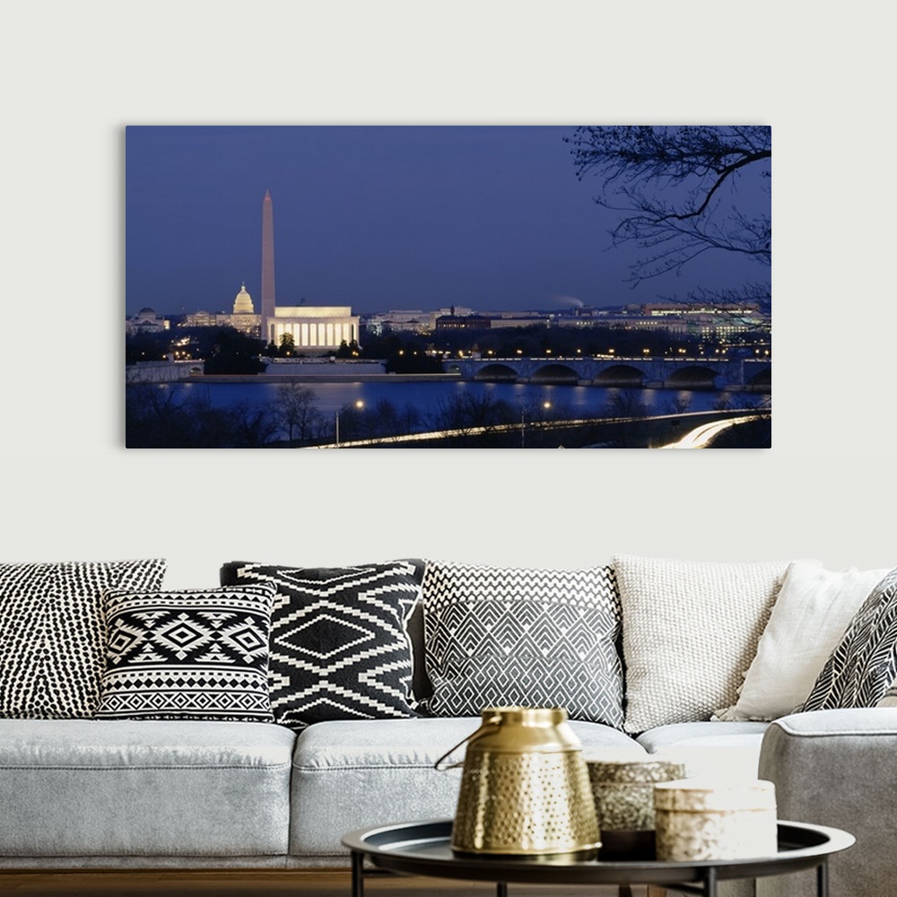 A bohemian room featuring Wall art of major illuminated DC landmarks layered in the distance of a waterfront that a bridge ...