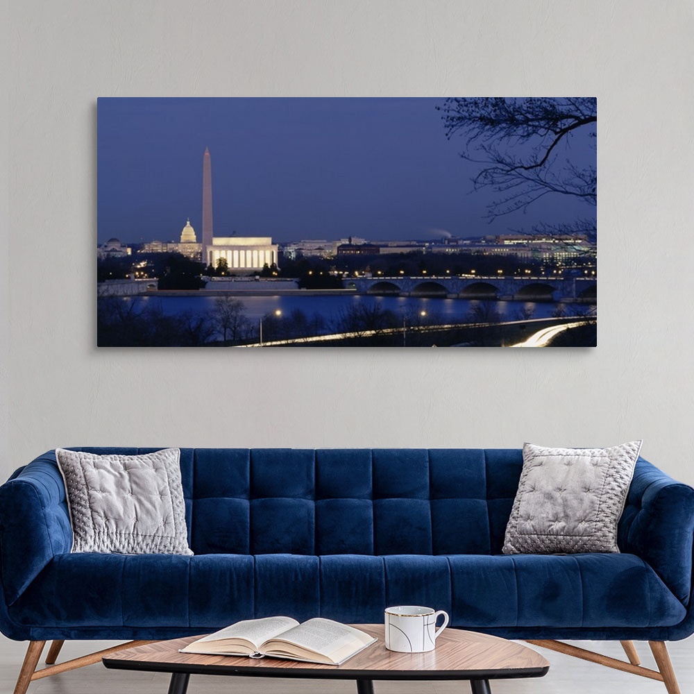 A modern room featuring Wall art of major illuminated DC landmarks layered in the distance of a waterfront that a bridge ...