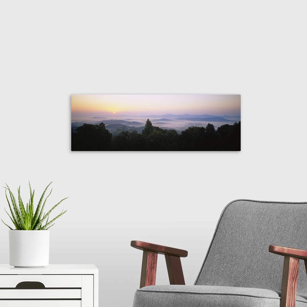 A modern room featuring Large panoramic photograph of mountains in Virginia with the sun setting far in the distance and ...