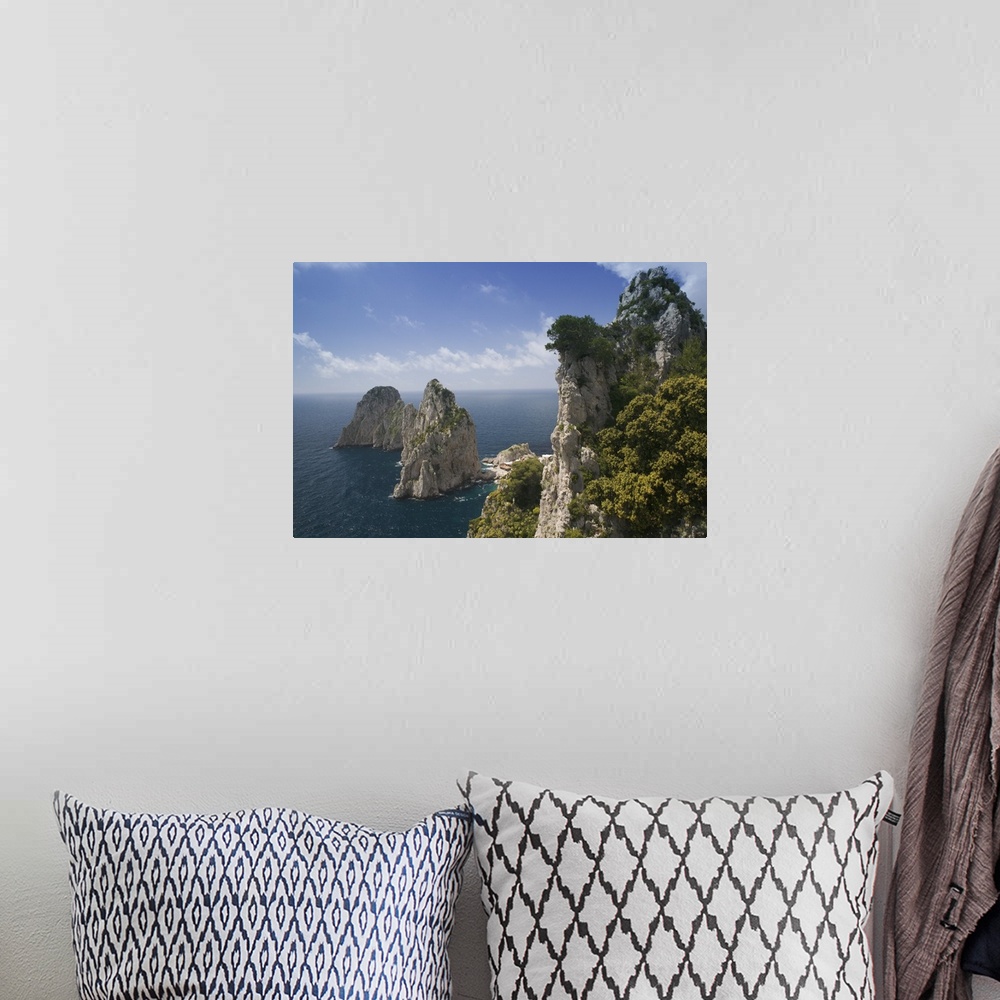 A bohemian room featuring Photograph of huge rock formations covered in trees in the ocean under a cloudy sky.