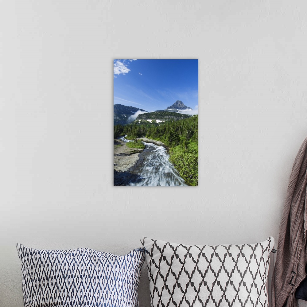 A bohemian room featuring High angle view of Siyeh Creek rushing through pine forest, distant Mount Reynolds against blue s...