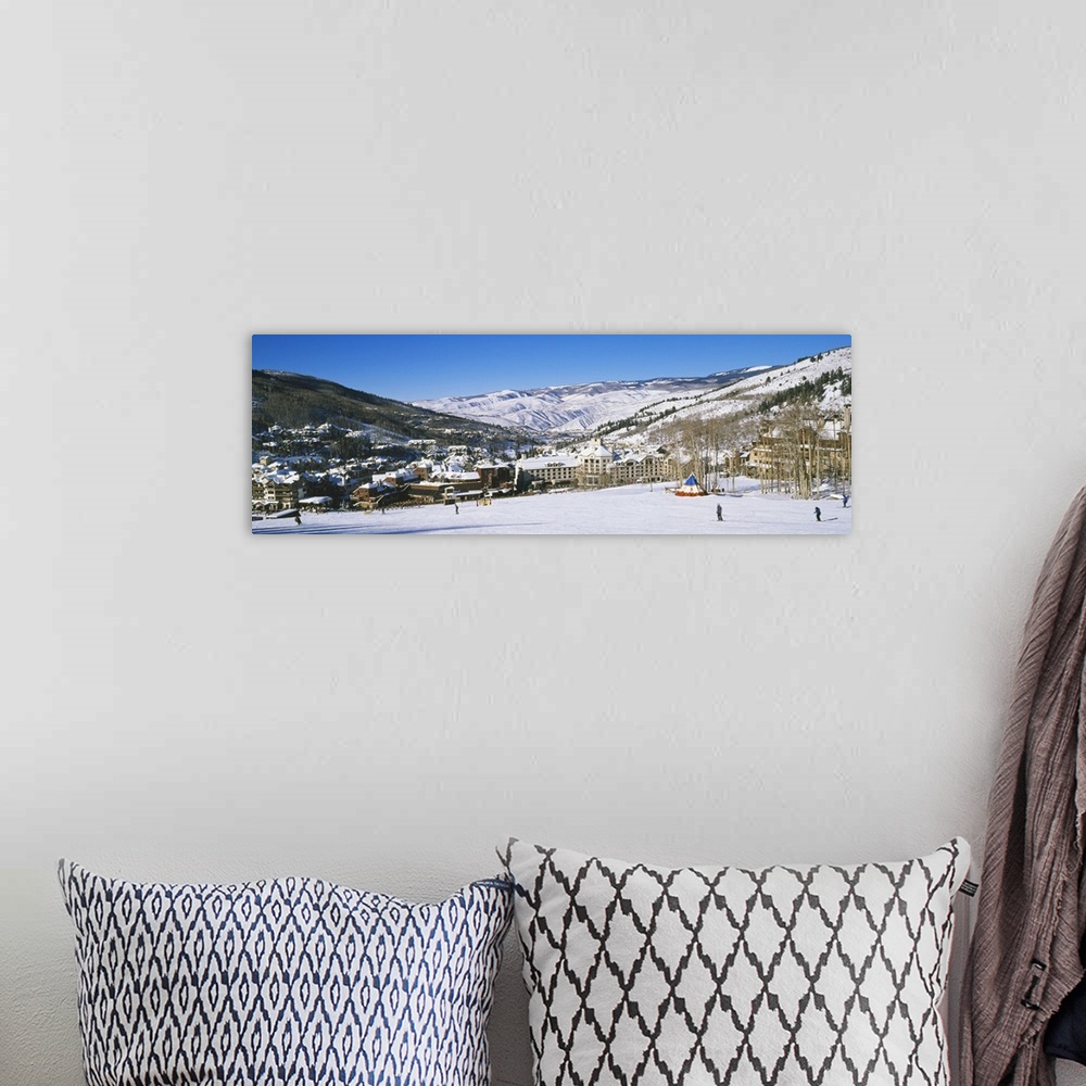 A bohemian room featuring Panoramic photograph of ski lodge nestled in the valley of snow covered mountains under a clear sky.