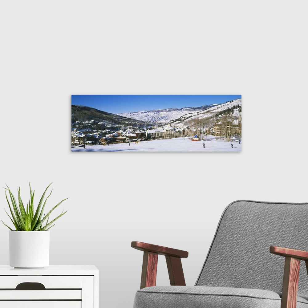 A modern room featuring Panoramic photograph of ski lodge nestled in the valley of snow covered mountains under a clear sky.