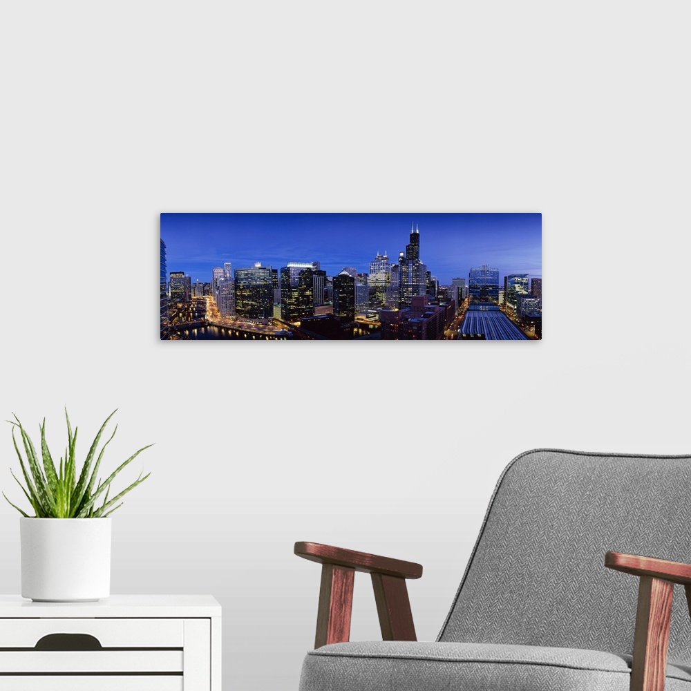 A modern room featuring Panoramic photograph at nighttime displays the bright buildings and high-rises that hover over th...