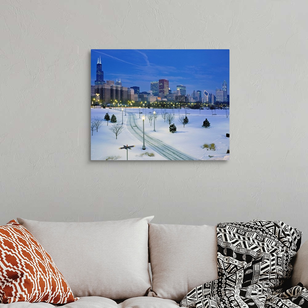 A bohemian room featuring A photograph of a city park buried in fresh snow and the city skyscrapers available of as a large...