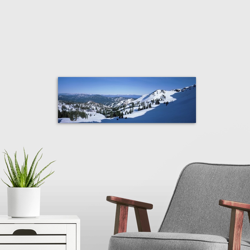 A modern room featuring A panoramic photograph looking down a snow covered mountain into the valley below.