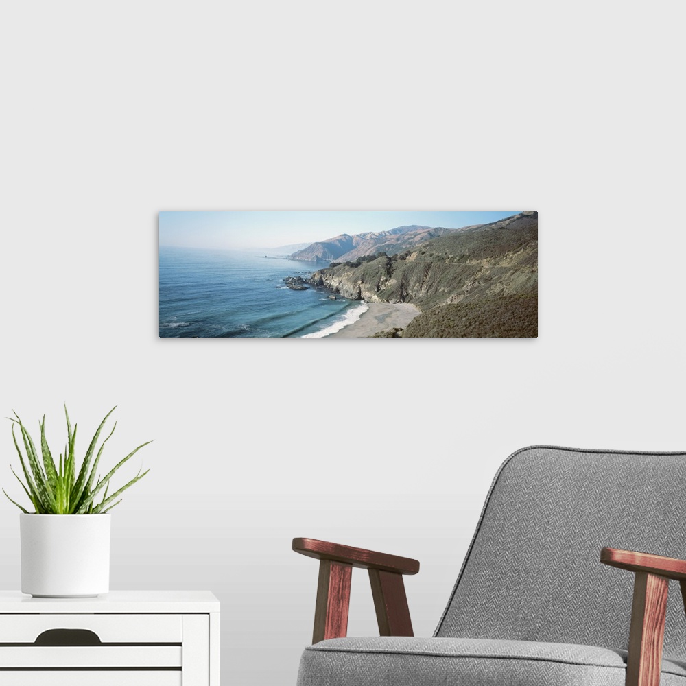 A modern room featuring Panoramic image of the Pacific Ocean meeting rocky cliffs and a smooth beach.