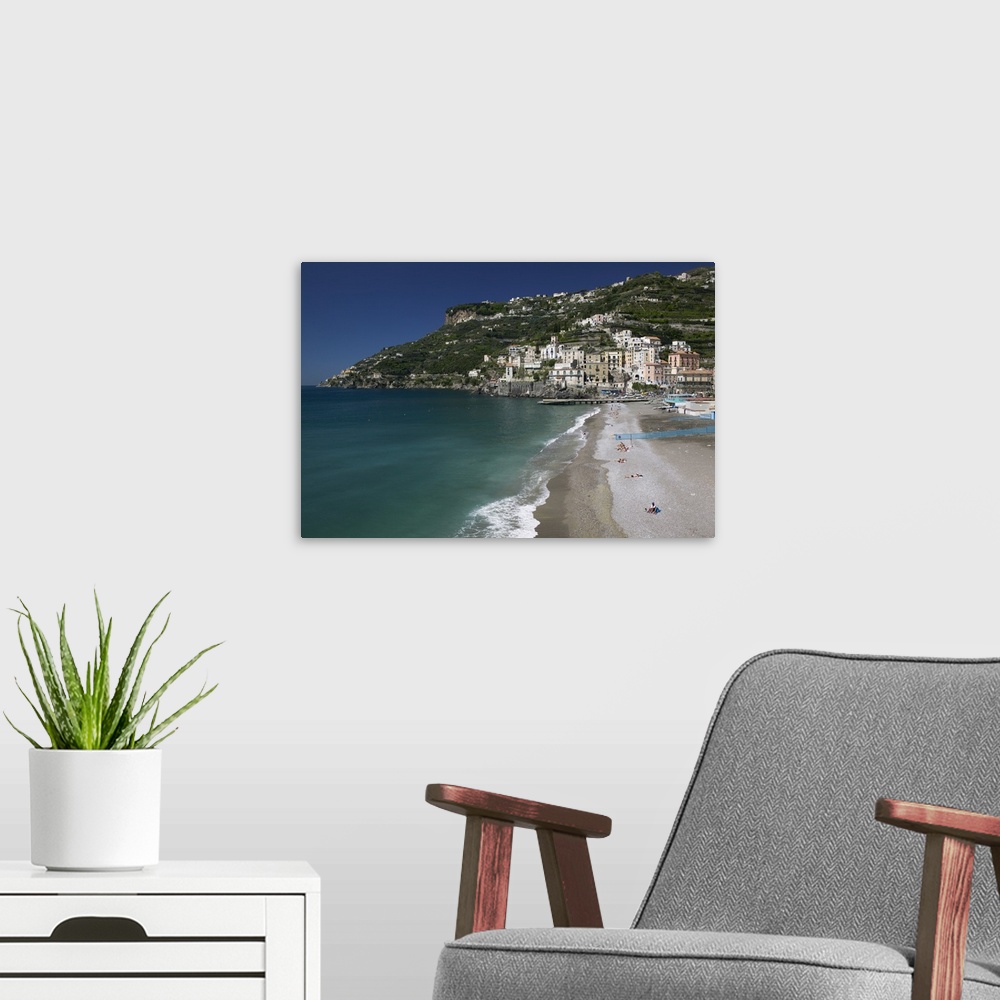 A modern room featuring A large cliff with buildings and homes built in it is photographed with the ocean water and beach...