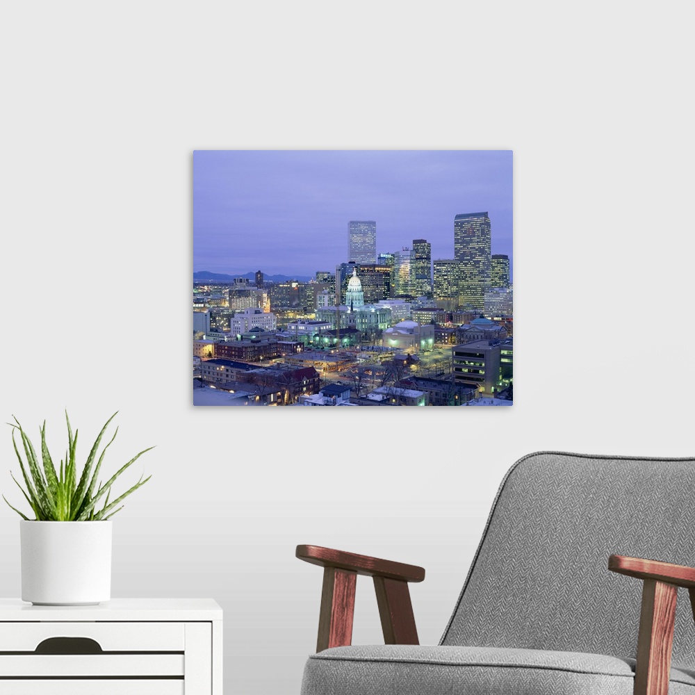 A modern room featuring Square canvas photo of a illuminated city at dusk with mountains in the left background.
