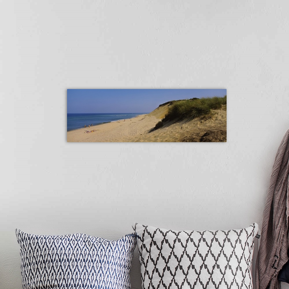 A bohemian room featuring Big, panoramic photograph of a grassy hillside, leading down to the beach and the shoreline where...
