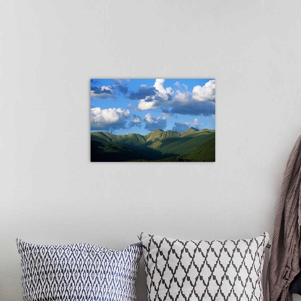 A bohemian room featuring Horizontal photograph on a giant canvas of a blue sky with fluffy clouds over the green, rolling ...