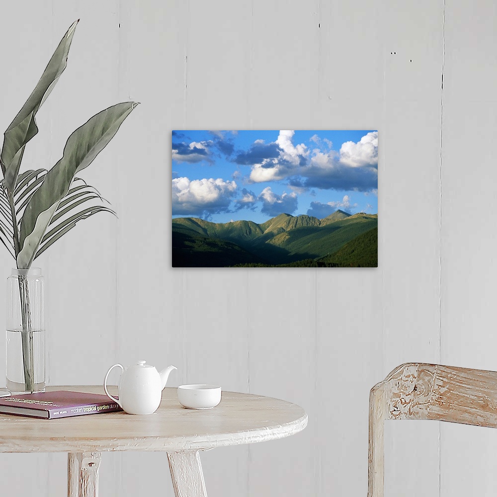 A farmhouse room featuring Horizontal photograph on a giant canvas of a blue sky with fluffy clouds over the green, rolling ...