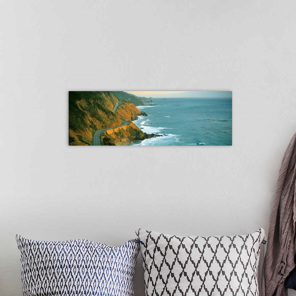 A bohemian room featuring Giant, landscape, panoramic photograph of Highway 1 curving through a cliffside near the shorelin...