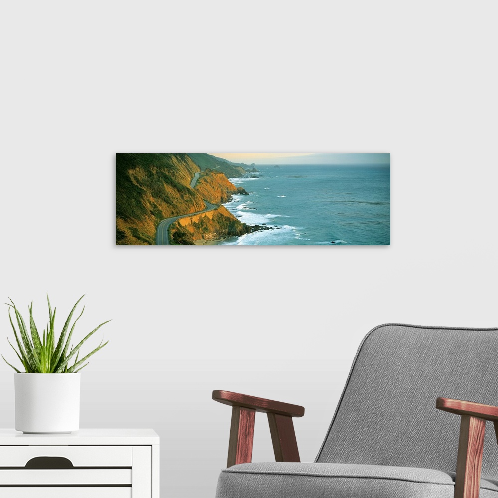 A modern room featuring Giant, landscape, panoramic photograph of Highway 1 curving through a cliffside near the shorelin...