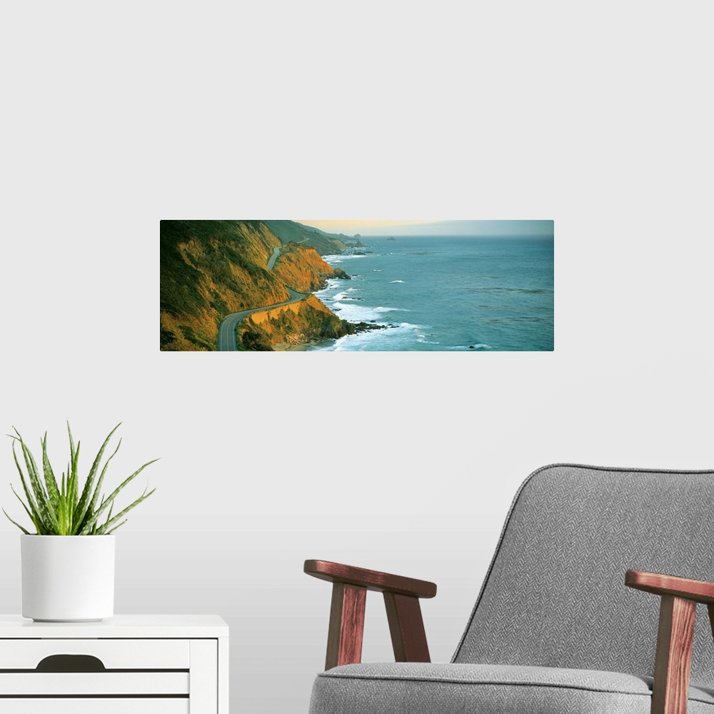 A modern room featuring Giant, landscape, panoramic photograph of Highway 1 curving through a cliffside near the shorelin...