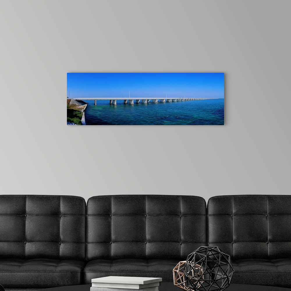 A modern room featuring Big panoramic photo print of a long bridge going over the ocean.