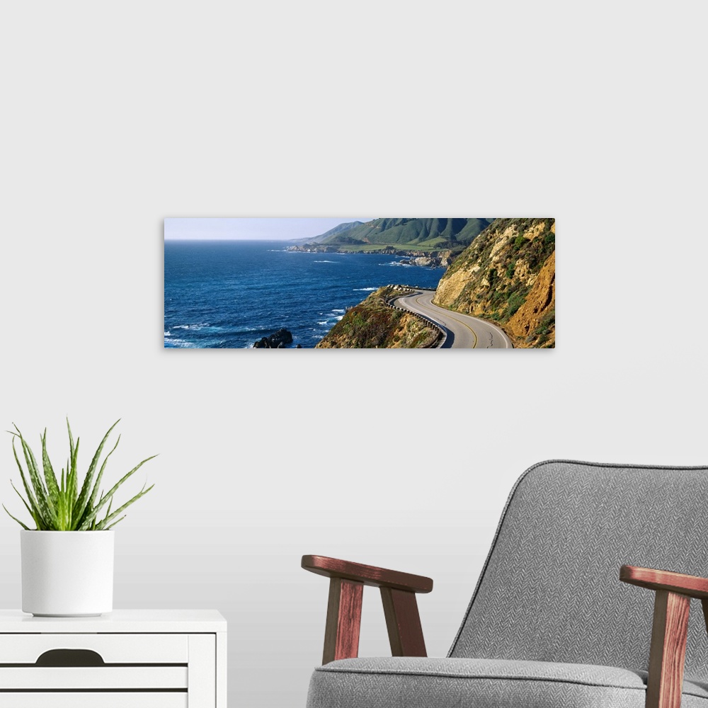 A modern room featuring Big, panoramic landscape photograph of curving Route 1 on a hillside, along the coast of Big Sur,...