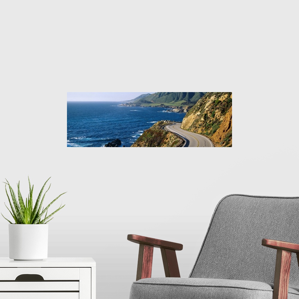 A modern room featuring Big, panoramic landscape photograph of curving Route 1 on a hillside, along the coast of Big Sur,...