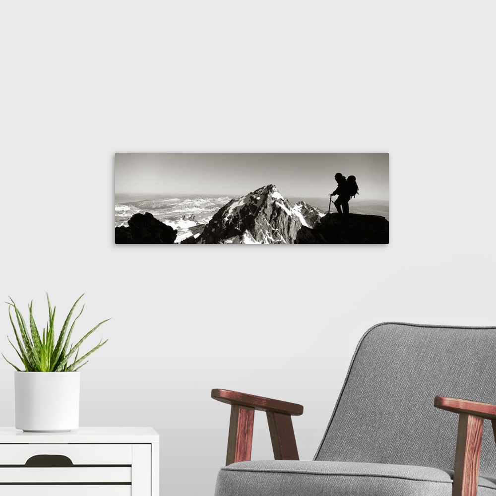 A modern room featuring This panoramic photograph shows mountain peaks and the silhouette of a climber surveying the land...