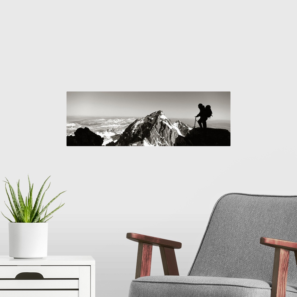 A modern room featuring This panoramic photograph shows mountain peaks and the silhouette of a climber surveying the land...