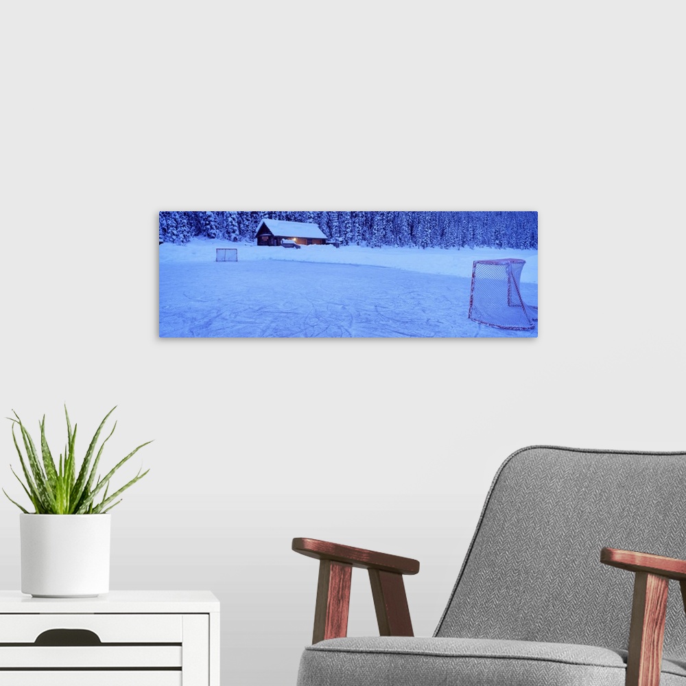 A modern room featuring Wall art for the home or cabin this panoramic photograph shows a cabin buried in snow next to a f...