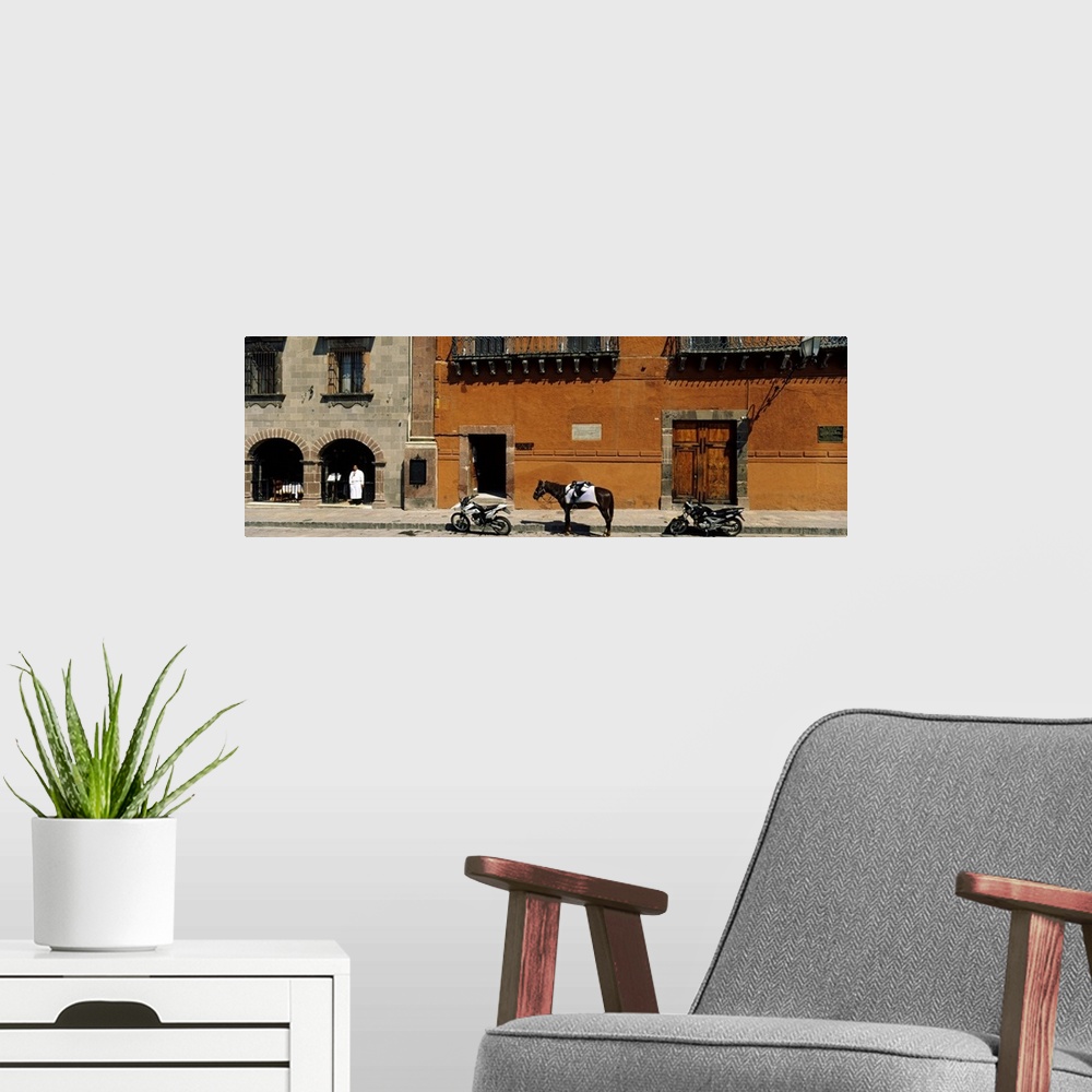 A modern room featuring This panoramic photograph shows two motorcycles sitting on a stone street with a horse standing i...