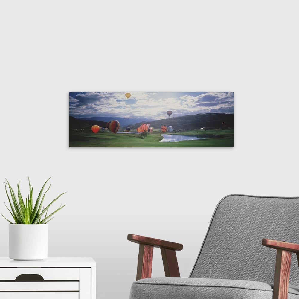 A modern room featuring This is a landscape photograph of hot air balloons lifting off from a field on the valley floor i...