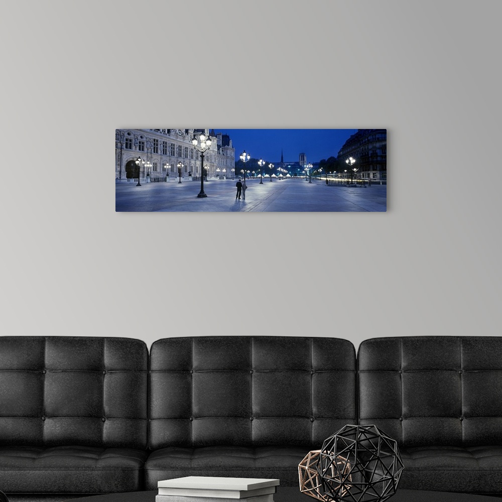 A modern room featuring Panoramic image of a street outside the Hotel de Ville lit up at night in Paris, France.