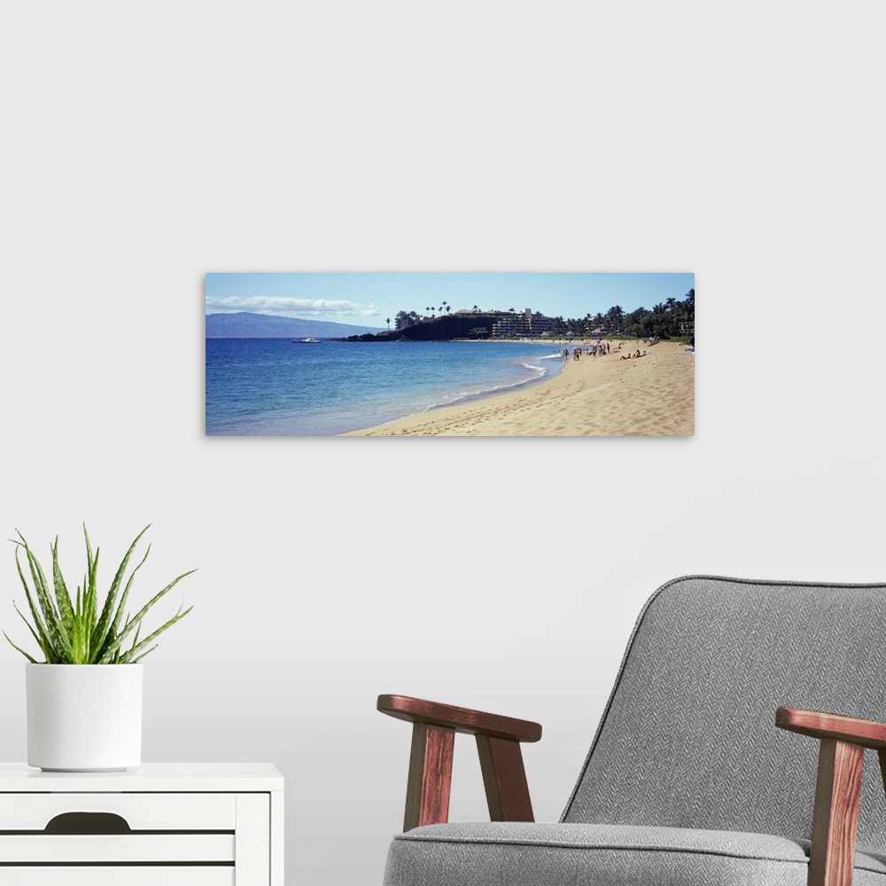 A modern room featuring Wide angle photograph taken of a Hawaiian coast with people on the beach and a hotel in the dista...