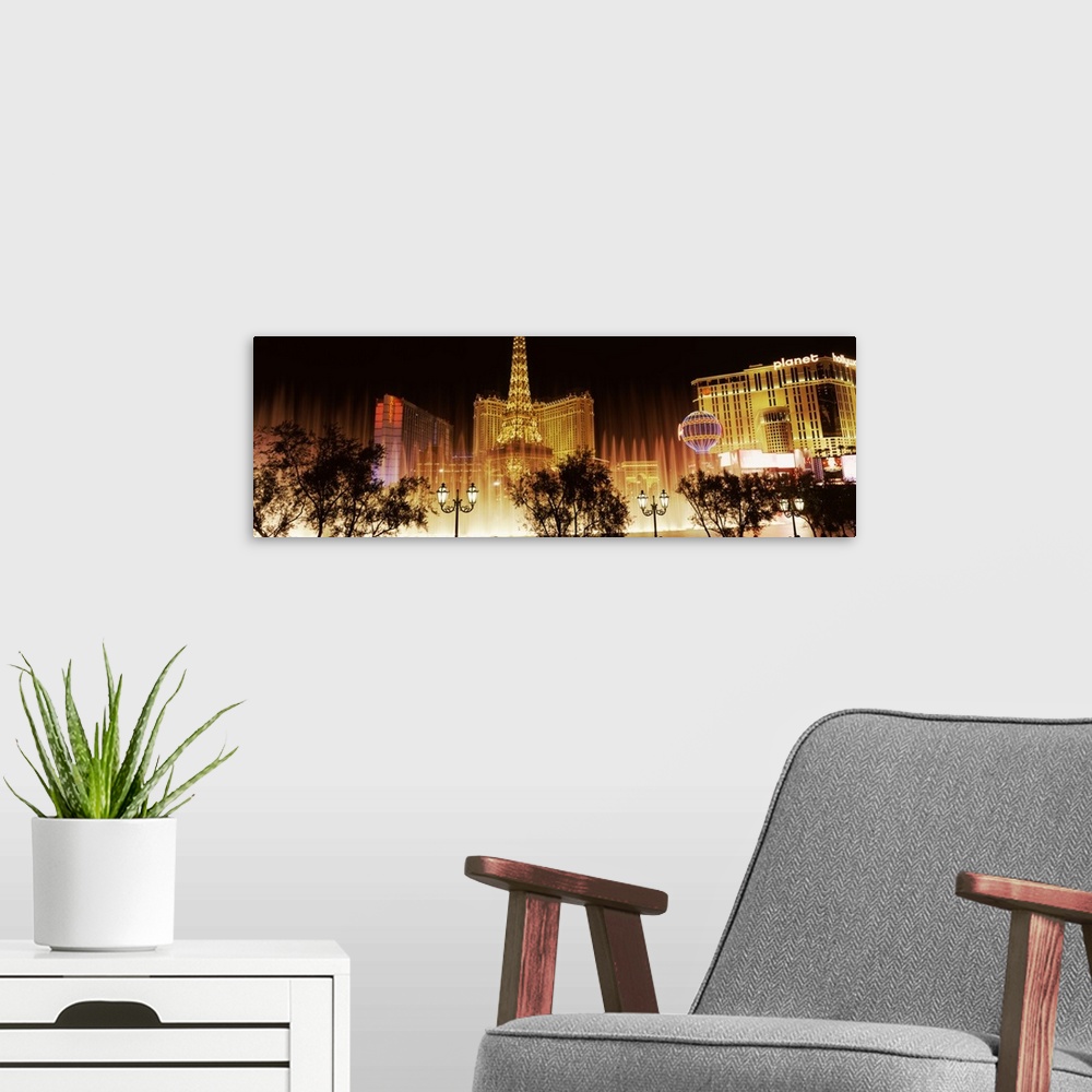 A modern room featuring Panoramic photograph of ""Sin City"" skyline and Bellagio fountains with tree and street lamp sil...