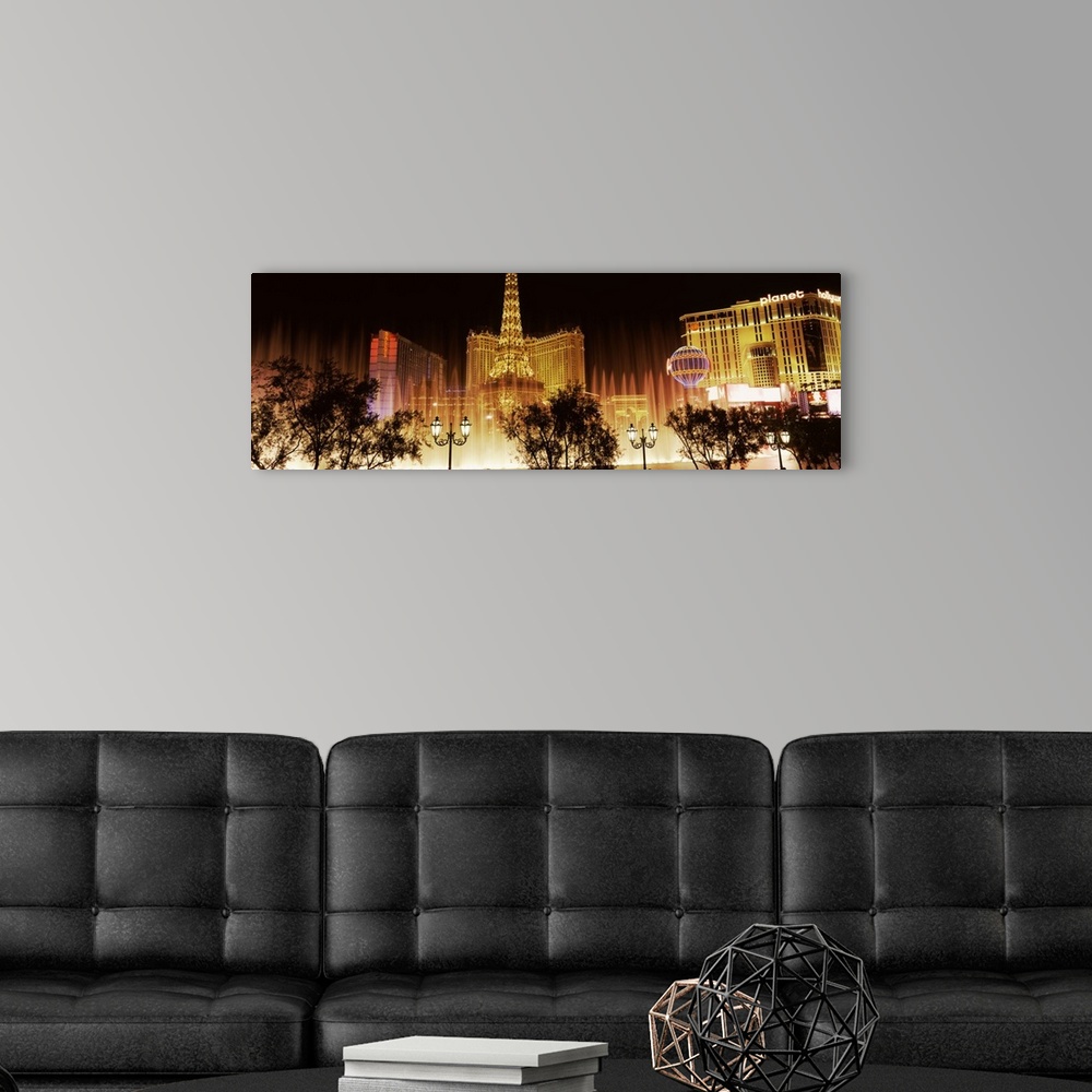 A modern room featuring Panoramic photograph of ""Sin City"" skyline and Bellagio fountains with tree and street lamp sil...