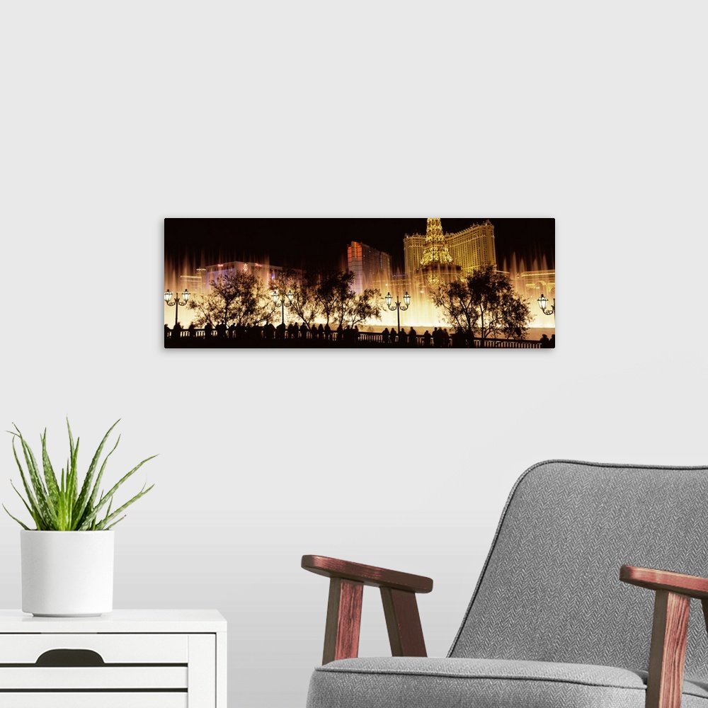 A modern room featuring Large panoramic photograph of the Las Vegas strip lit up with the silhouette of people and trees ...