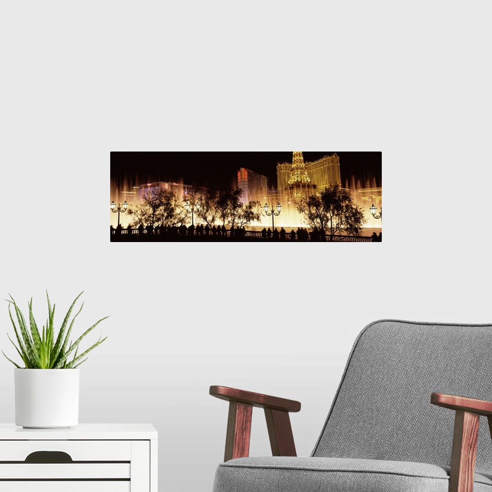 A modern room featuring Large panoramic photograph of the Las Vegas strip lit up with the silhouette of people and trees ...