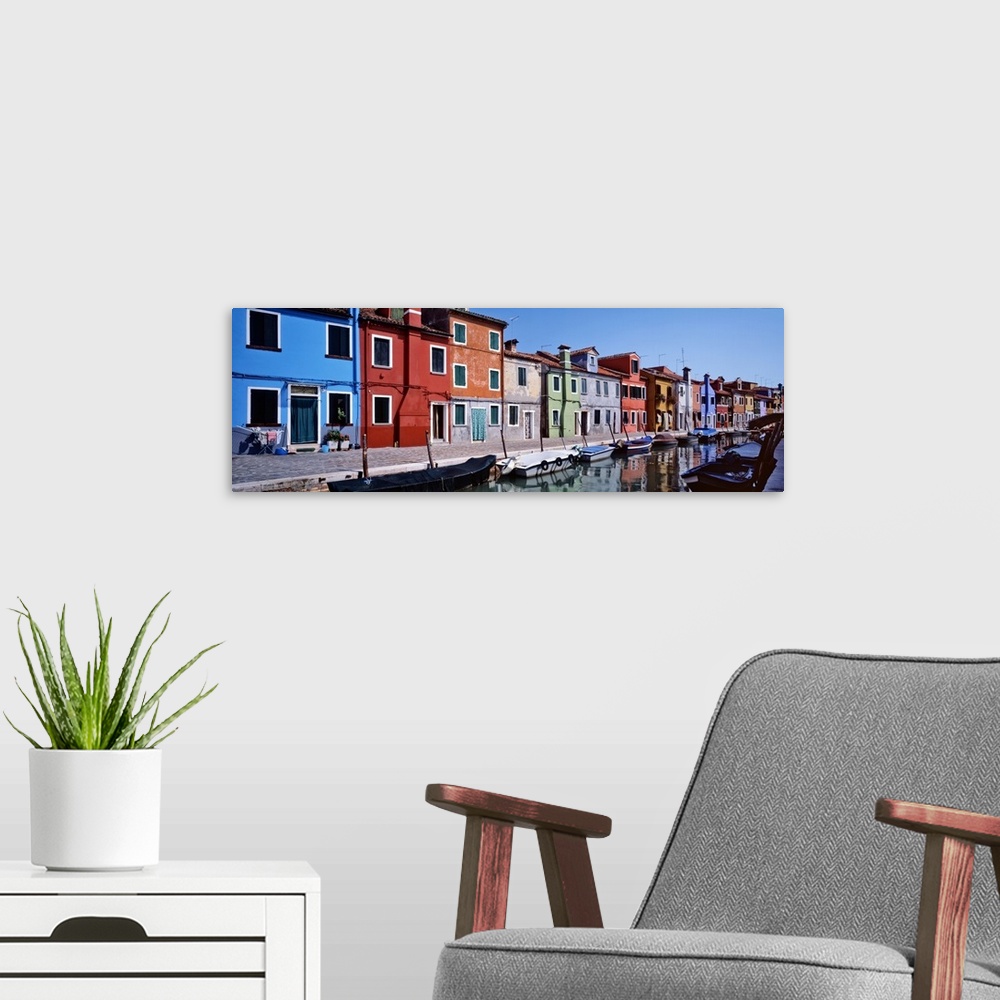 A modern room featuring Panoramic photograph of colorful houses lined up next to each other on a lagoon with boats tied u...