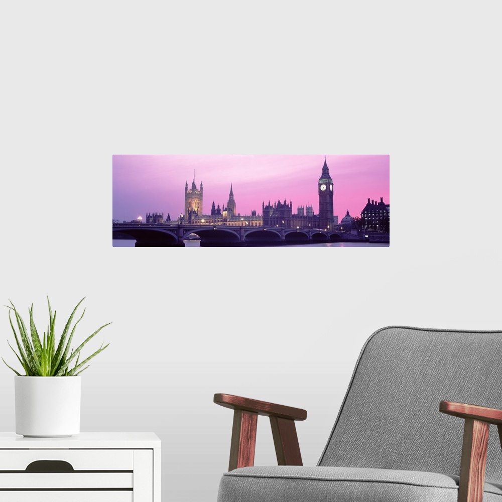 A modern room featuring London Skyline in the evening. Thames river in foreground with Big Ben, Halls of Parliament. The ...